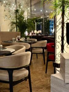 a restaurant with tables and chairs and plants at Hotel AVENUE in Ravda
