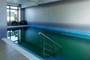 a large swimming pool with blue tiles on the wall at Hotel Doina 2 Tasnad in Tăşnad