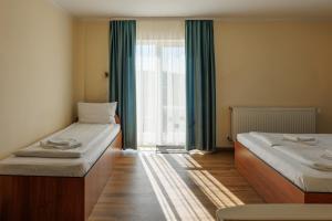 a room with two beds and a large window at Hotel Doina 2 Tasnad in Tăşnad