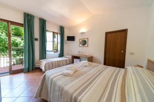 a hotel room with two beds and a window at Hotel Voce del Mare in Capoliveri