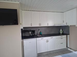 a kitchen with white cabinets and a sink and a microwave at Boende i Falkenberg in Falkenberg