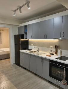 a kitchen with gray cabinets and a black refrigerator at Floor Villa 2 in Vlorë