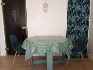 a table with two chairs and a green table cloth on it at Appartement T1 et petite terrasse in Artiguelouve +4 photos