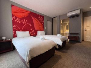 ein Hotelzimmer mit zwei Betten und einer roten Wand in der Unterkunft Urbanight Boutique Hotel in Bloemfontein + 16 Fotos