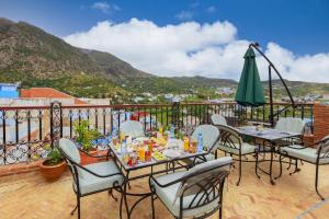 a patio with tables and chairs and a green umbrella at Riad Sultan Chefchaouen in Chefchaouen
