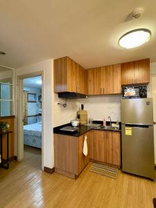a kitchen with wooden cabinets and a stainless steel refrigerator at Aesthetic 2 Bedroom The Loop Tower Condo Unit in Cagayan de Oro +14 photos