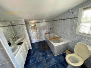 a bathroom with a toilet and a tub and a sink at Le Cocon des Forges in Talmont
