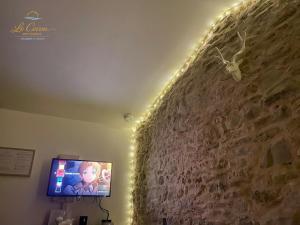 a tv in a room with a stone wall at Le Cocon des Forges in Talmont