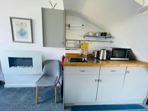a kitchen with white cabinets and a sink and a chair at Godrevy Lighthouse View, Carbis Bay, St Ives, free parking, sea view in Carbis Bay