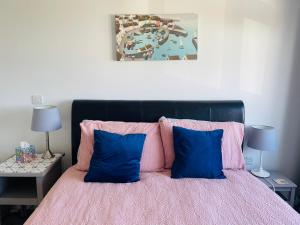 a bedroom with a pink bed with two blue pillows at Godrevy Lighthouse View, Carbis Bay, St Ives, free parking, sea view in Carbis Bay