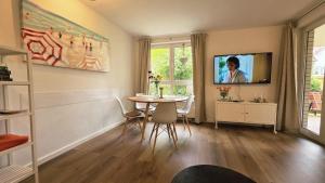 a living room with a table and a tv on the wall at Strandperle in Timmendorfer Strand
