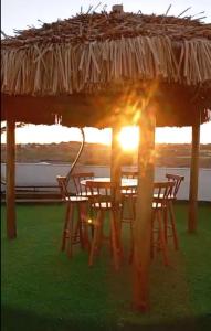 a group of tables and chairs under a straw umbrella at Refúgio Tropical in Touros