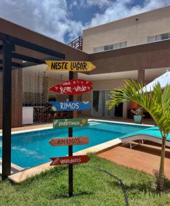 a directional sign in front of a swimming pool at Refúgio Tropical in Touros
