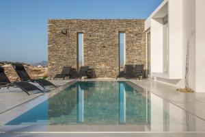 a swimming pool with chairs and a building at THEIA VILLA in Adamantas