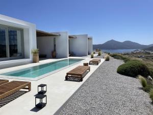 a swimming pool with benches next to a house at THEIA VILLA in Adamantas