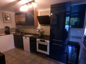 a kitchen with a black refrigerator and a stove at Maison des Roses in Béalencourt
