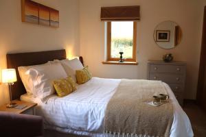 a bedroom with a white bed with a window at Modern, eco friendly house in Kildonan on Skye in Flashader