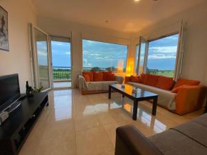 a living room with orange furniture and large windows at Olyvia in Plaka Litochorou