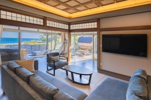 a living room with a couch and a flat screen tv at 鵜原館 -Ubarakan- in Katsuura