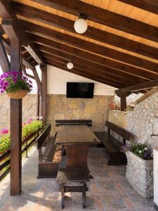 a patio with a wooden table and a tv on a stone wall at Комплекс Света Гора in Oreshak