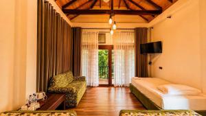 a bedroom with a bed and a couch and a chair at Gatetrees resort in Jaffna