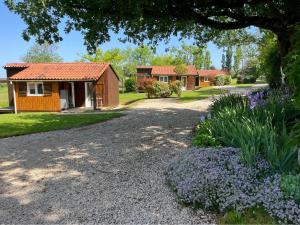 a house and some flowers in front of a driveway at Les chalets du Causse Confort Climatisé in Gelle