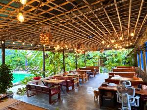 a restaurant with wooden tables and chairs and a pool at Rocky Mountain Ecolodge in Xuân Sơn