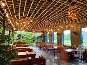 a restaurant with wooden tables and chairs and lights at Rocky Mountain Ecolodge in Xuân Sơn