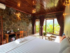 a bedroom with a large bed and a stone wall at Rocky Mountain Ecolodge in Xuân Sơn +55 photos