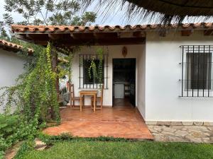 a patio of a white house with a table and chairs at Casita de Piedra in Atyrá