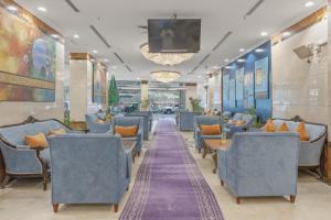 a waiting room with blue chairs and a flat screen tv at Amjad Al Deafah Hotel in Mecca