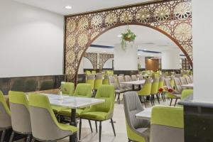 a restaurant with white tables and green chairs at Amjad Al Deafah Hotel in Mecca