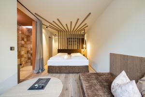 a hotel room with two beds and a couch at Loewe Dolomites in San Candido