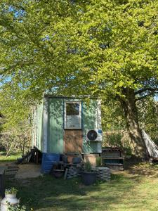 an old green trailer sitting under a tree at Tiny house close to Copenhagen in Nybølle