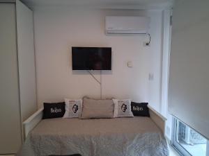 a bedroom with a bed with pillows and a tv at LENNON SUITE remis free Ezeiza in Ezeiza