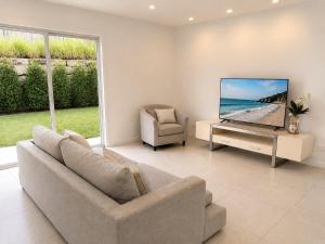 a living room with a couch and a tv and a chair at 17 Pimpama Home in Pimpama