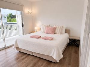 a bedroom with a large white bed with two pink pillows at 17 Pimpama Home in Pimpama