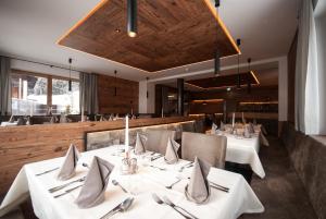 a dining room with white tables and chairs at Loewe Dolomites in San Candido