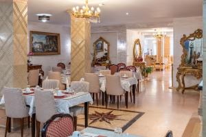 a restaurant with tables and chairs and a chandelier at HOTEL ROYAL Paris Ivry in Ivry-sur-Seine