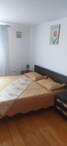 a bed in a bedroom with a wooden floor at Casa Bunicilor in Moldoviţa