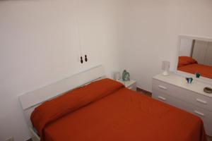 1 dormitorio con cama de color naranja y espejo en Iaia Apartment, en Sciacca