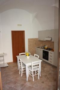 una cucina con tavolo e sedie bianchi in una stanza di Iaia Apartment a Sciacca
