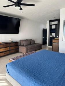 a bedroom with a blue bed and a couch at Vistas del Angel in San Juan Cosalá