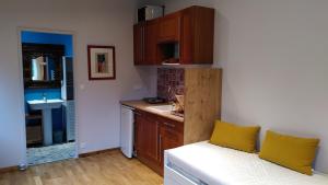 a kitchen with a white couch and a kitchen with a sink at La cabane Rouge in La Queue-dʼHaye