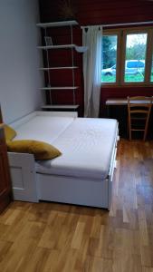 a white bed in a room with a wooden floor at La cabane Rouge in La Queue-dʼHaye