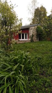 a small red and white house in a yard at La cabane Rouge in La Queue-dʼHaye