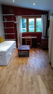 a bedroom with a bed and a desk and a table at La cabane Rouge in La Queue-dʼHaye