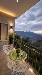 a table and chairs on a balcony with a view at Hotel Himalayan Heaven - A Most Luxury & Best Mountain View Hotel In Mussoorie By lilly in Mussoorie
