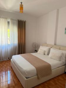 a bedroom with a large white bed and a window at Sea You Soon Apartment in Shëngjin