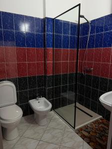 a bathroom with a toilet and a glass shower at Sea You Soon Apartment in Shëngjin +17 photos